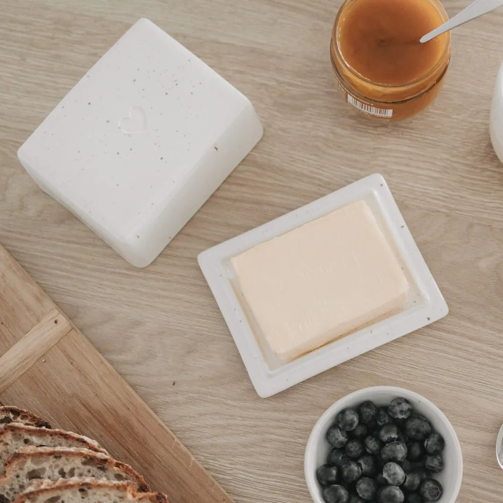 Draufsicht auf eine offene Butterdose mit Brot, Beeren in einer Schale und einem Glas Aufstrich