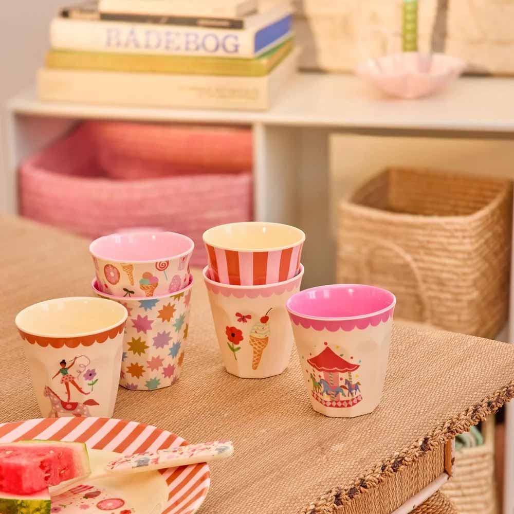 Sechs Rice Fun-Fair-Becher in Rosa und Creme mit unterschiedlichen Motiven auf einem Tisch