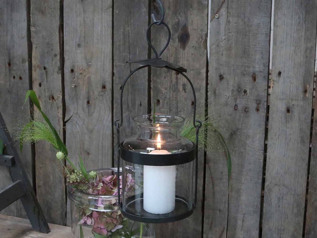 Schwarze Chic Antique Flaschenlaterne mit Glas und Kerze vor einer rustikalen Holzwand