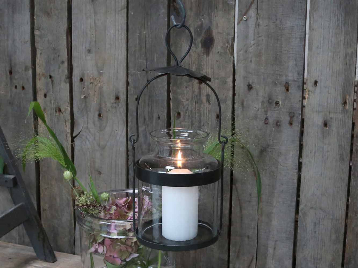 Schwarze Chic Antique Flaschenlaterne mit Glas und Kerze vor einer rustikalen Holzwand