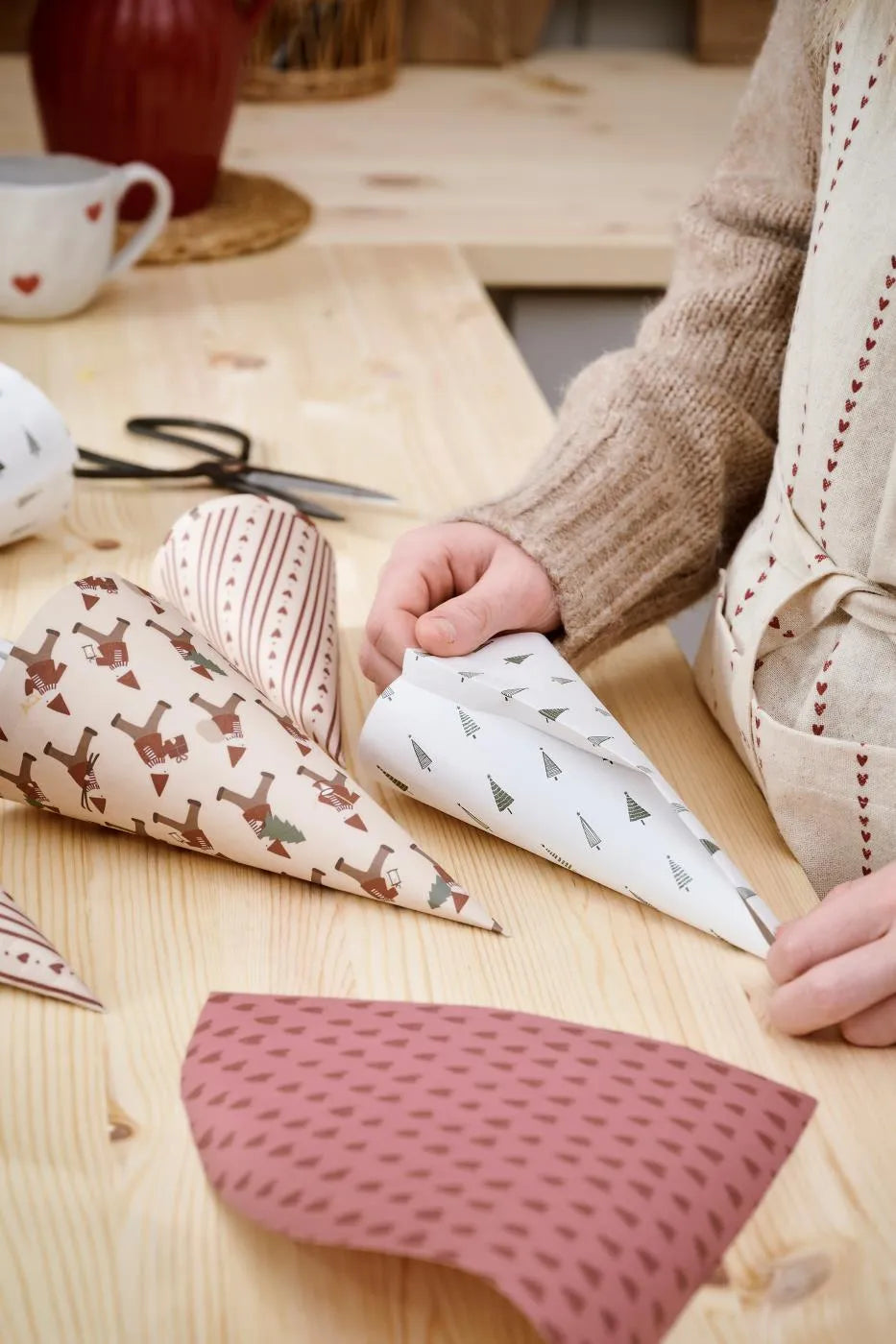 Geschenke werden mit gemustertem Ib-Laursen-Papier am Holztisch eingewickelt
