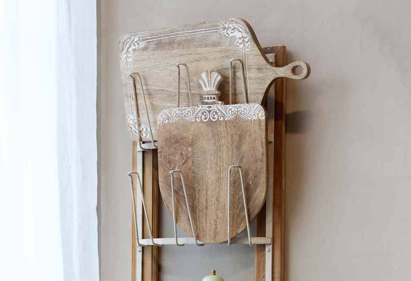 Eine Sammlung alter Holzschneidebretter, die an einer beigen Wand lehnen.