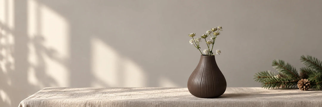 Braune gerillte Ekenäs-Vase von Storefactory mit zarten Blumen auf einem hellen Tisch