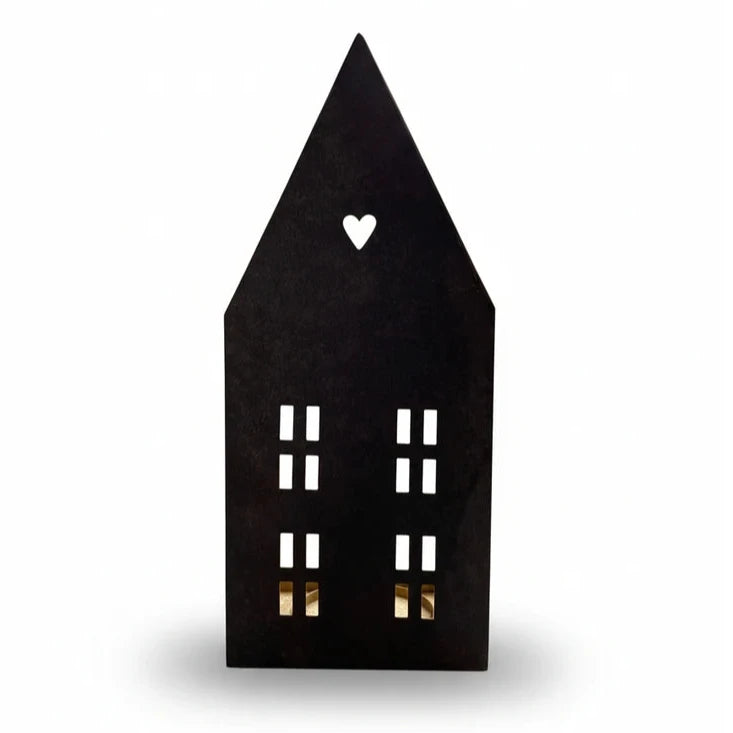Das Alsaba Home - Lichthaus für Kerzen aus Metall in Schwarz-Gold ist eine schwarze Laterne in Form eines Metallhauses mit einem Herzausschnitt in der Nähe des Daches und rechteckigen Fensterausschnitten auf der Vorderseite.