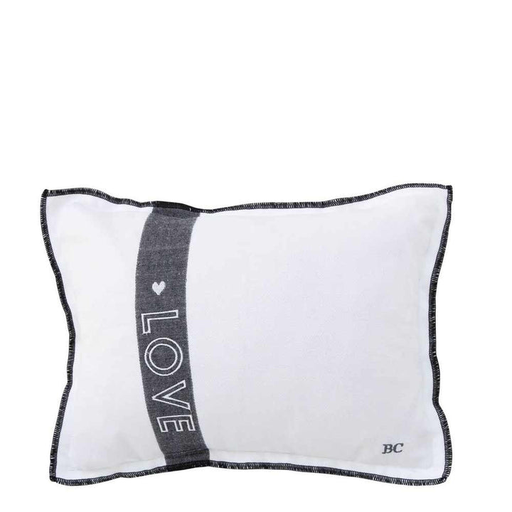 Weißes rechteckiges Bastion Collection - Kissen Love 25 x 35 cm mit Füllung mit schwarzer Paspel, verziert mit einem vertikalen schwarzen Streifen mit dem Wort „LOVE“ und einem kleinen Herz. Die Initialen „BC“ befinden sich in der unteren rechten Ecke.