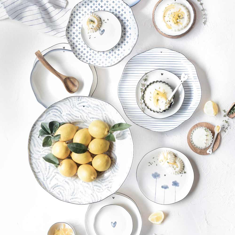 Eine Draufsicht auf einen gedeckten Tisch mit Bastion Collections – Dessertteller Iris Blue Poppy-Tellern, Zitronen und weichgekochten Eiern, arrangiert in einem leichten, minimalistischen Stil.