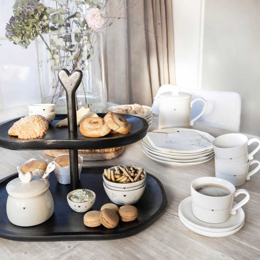 Ein gedeckter Tisch mit einer Bastion Collections - Etagere Groß Holz Natur, auf der Gebäck, Brot und verschiedene Snacks liegen. Tassen, Untertassen, ein Topf und Besteck sind ordentlich angeordnet. Im Hintergrund steht eine Vase mit Blumen.