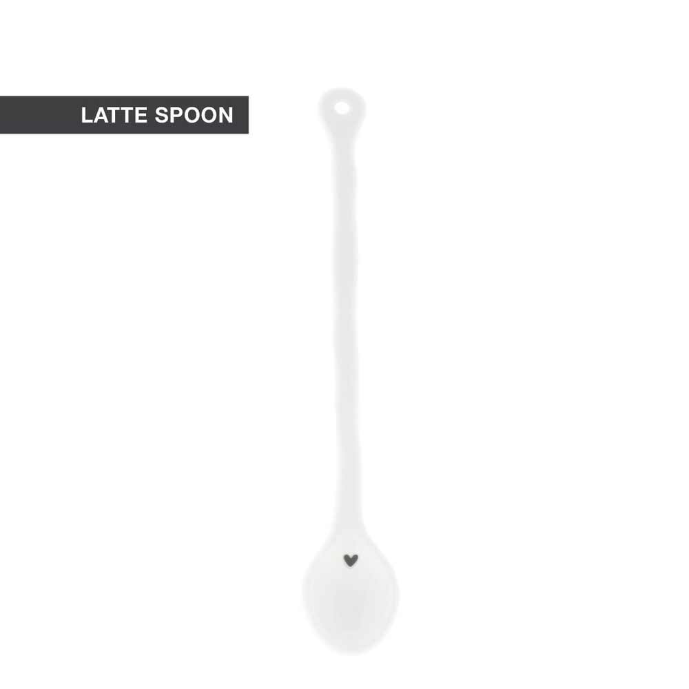 Vor einem schlichten Hintergrund ist ein langer weißer Latte-Löffel mit einem kleinen Herz am unteren Ende des Griffs und der Aufschrift „Bastion Collections – Löffel für Latte Macchiato Herz wellenförmig“ abgebildet.