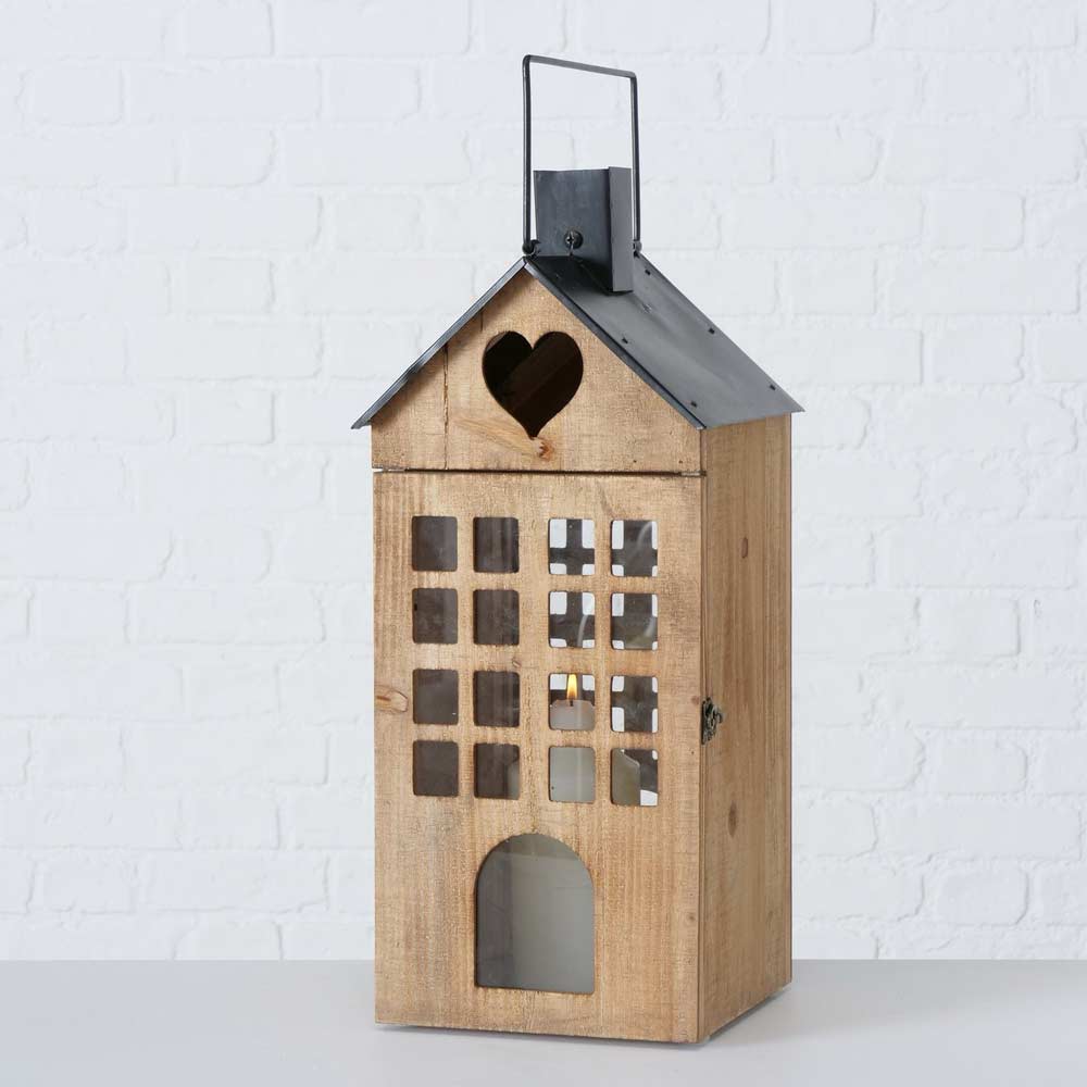 Die Boltze - Laterne Brixen Haus ist eine Holzlaterne in der Form eines Hauses mit quadratischen Ausschnitten auf der Vorderseite, einem herzförmigen Ausschnitt unter dem Metalldach und einem kleinen Riegel an der Seite.