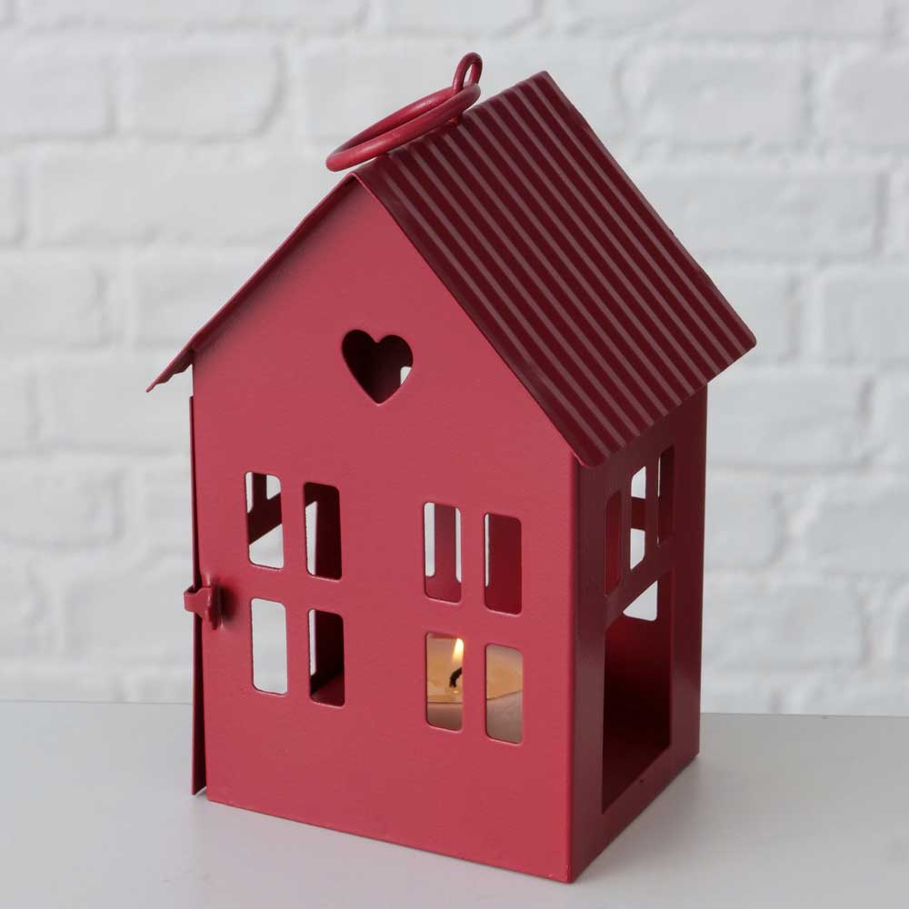 Das Boltze - Metallhaus Herz in Dunkelrot, Teil eines 2-teiligen Sets, hat die Form eines Hauses mit ausgeschnittenen Fenstern und einem Herzmotiv, positioniert auf einer weißen Fläche vor einer Ziegelmauer-Kulisse.
