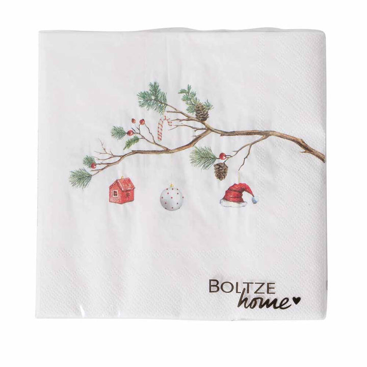 Eine weiße Serviette mit dem Namen „Boltze – Papierserviette Weihnacht mit Tannenzweig“ zeigt ein weihnachtliches Design mit einem Zweig, Ornamenten, einem roten Haus, einer Weihnachtsmannmütze und Tannenzapfen sowie den Text „Boltze home“.