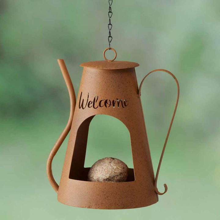 Wir präsentieren die Boltze - Vogelfutterstation Welcome Kanne Rost, ein rustikales Vogelfutterhäuschen aus Metall in Form einer Teekanne mit „Willkommen“-Ausschnitt und einer Kette zum Aufhängen. Es wird mit einer runden Futterkugel geliefert, um Vögel anzulocken.