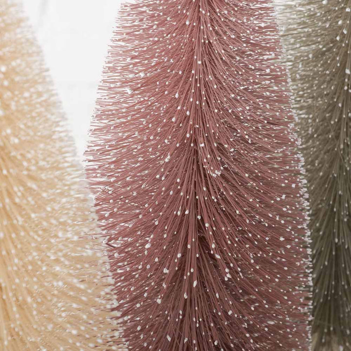 Nahaufnahme von drei Weihnachtsbaumen „Vintage Pastell“ von Boltze in den Farben Beige, Rosa und Grün mit kleinen weißen Flecken, die an Schnee erinnern. Alle stehen auf Holzsockeln und sind 40 cm hoch.