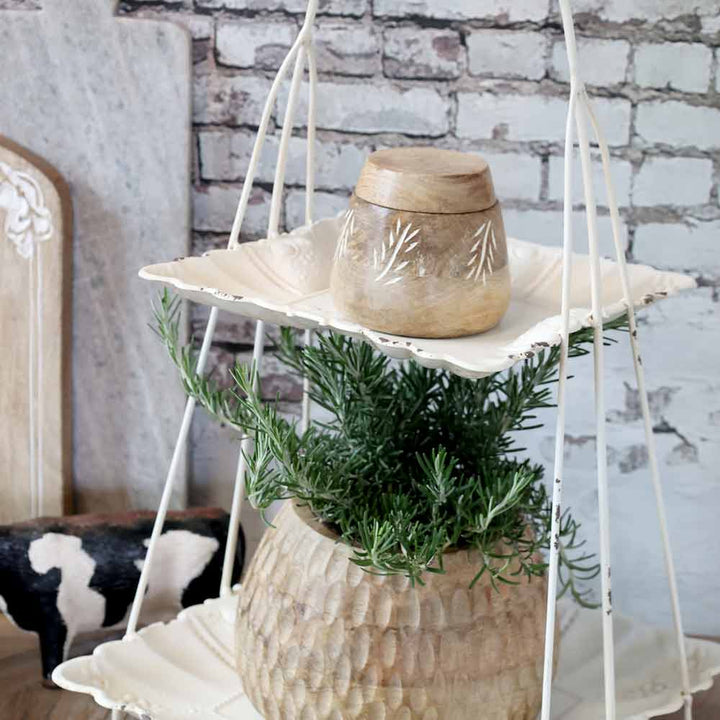 Eine Chic Antique – Etagere mit Henkel präsentiert einen üppig grünen Kräutertopf und ein kleines Holzgefäß vor einer weißen Backsteinwand und schafft so eine rustikale Deko-Szene.