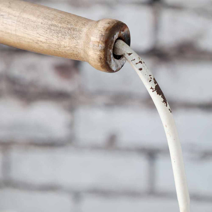 Nahaufnahme einer Chic Antique – Etagere mit Henkel, in die eine geschälte, weiße Metallstange eingesetzt ist, vor einem unscharfen Ziegelhintergrund.