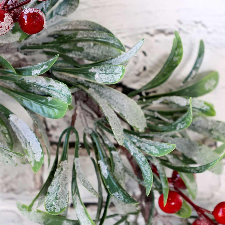 Nahaufnahme des Chic Antique – Fleur Kranz mit Schnee und Beeren 37 cm, mit bereiften Blättern und roten Beeren vor einem weißen strukturierten Hintergrund.