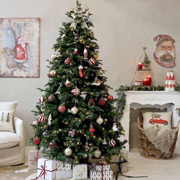 Ein wunderschön dekorierter Weihnachtsbaum mit roten und weißen Ornamenten und funkelnden Lichtern steht stolz im Wohnzimmer. An der Wand sorgt ein festliches Weihnachtsmann-Gemälde für Weihnachtsstimmung, während Geschenke unter dem Baum verstreut liegen. Der Kaminsims ist fröhlich mit saisonalem Dekor geschmückt, darunter ein schicker Chic Antique - Kissebezug Weihnachtsauto Leinen 50 x 50 cm für eine gemütliche Note.
