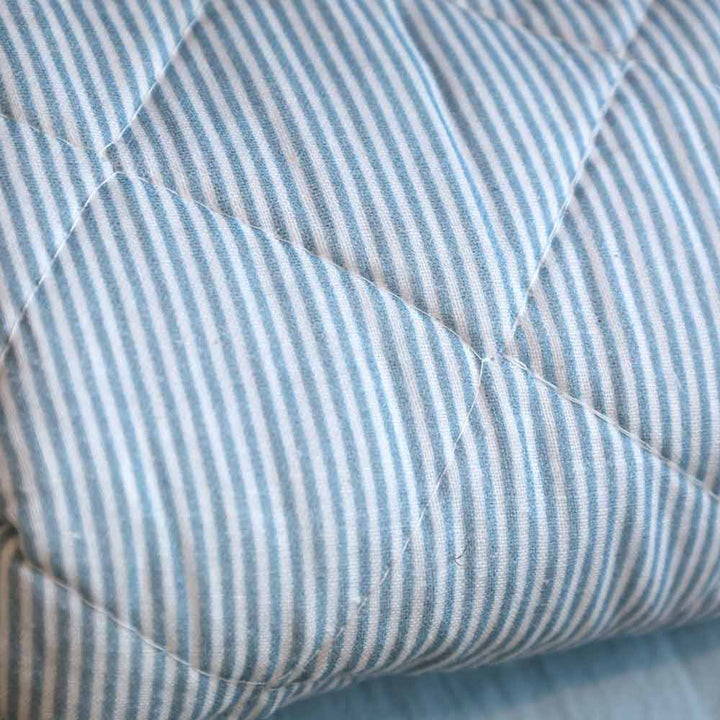 Nahaufnahme des Chic Antique Quilt Maritimes Streifenmuster Sky Blue (180 x 130 cm) mit hellblauen und weißen vertikalen Streifen auf gestepptem Stoff.