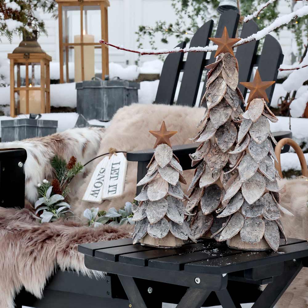 Der Weihnachtsbaum mit Stern von Chic Antique ziert zusammen mit Felldecken, Laternen und Grünpflanzen eine schneebedeckte Gartenbank und schafft so eine gemütliche Winterlandschaft.