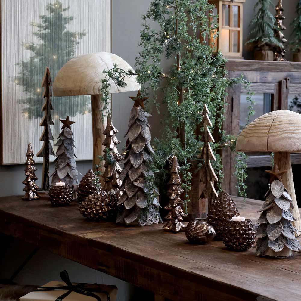 Chic Antique – Weihnachtsbaum mit Stern und großem Pilzdekor auf einem rustikalen Holztisch, umgeben von Grün, in einem gemütlichen Innenbereich.
