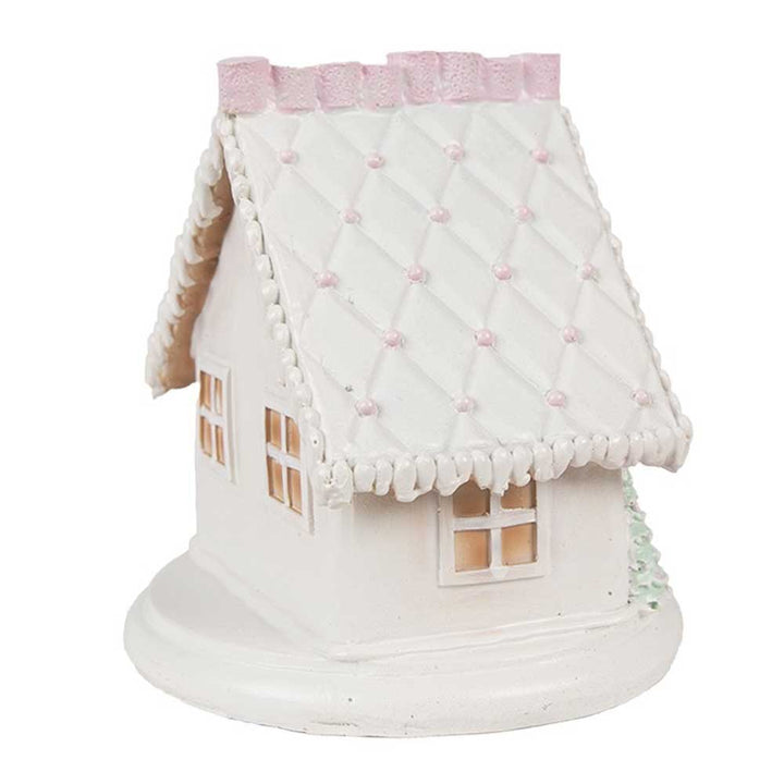 Das Clayre & Eef - Lebkuchenhaus mit LED 13 cm ist ein kleines, weißes Keramikhausmodell mit gestepptem Dachdesign und quadratischer Basis. Dieses charmante Stück verfügt über zwei sichtbare Fenster und zarte rosa Details auf dem Dach.