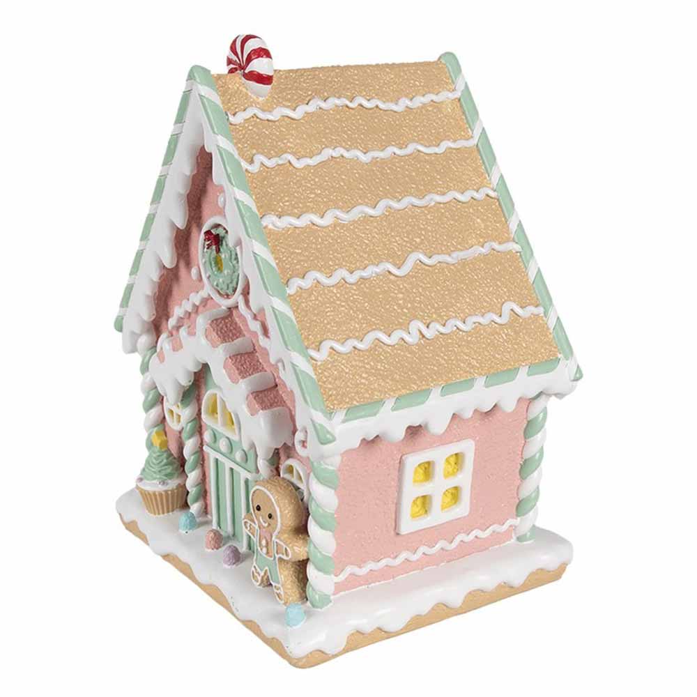 Das Lebkuchenhaus Pastell 25 cm von Clayre & Eef ist ein dekoratives Lebkuchenhaus in Pastellfarben, geschmückt mit Süßigkeiten-Akzenten, einer Lebkuchenfigur und einer Zuckerstange auf dem Dach.