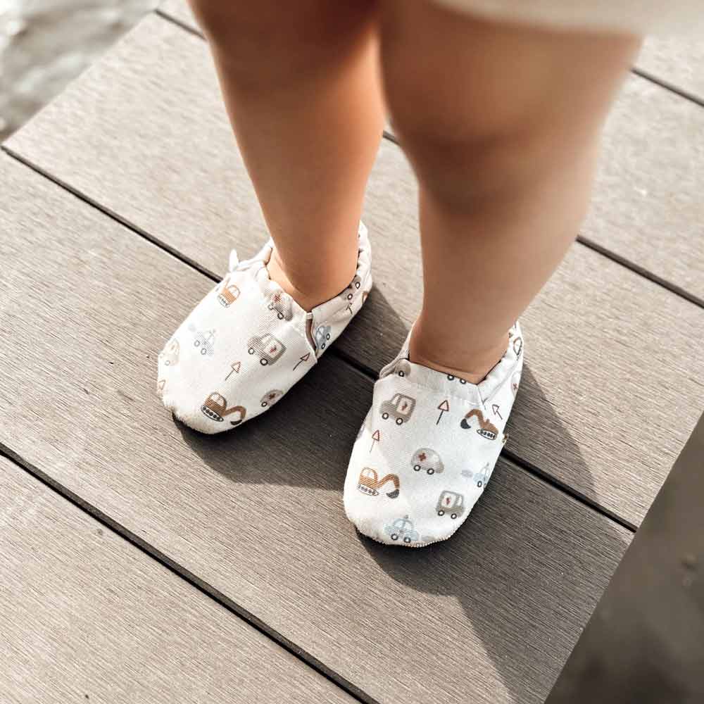 Kleinkind trägt Cozy Roots - Lauflernschuhe Little Driver steht auf einem Holzdeck.