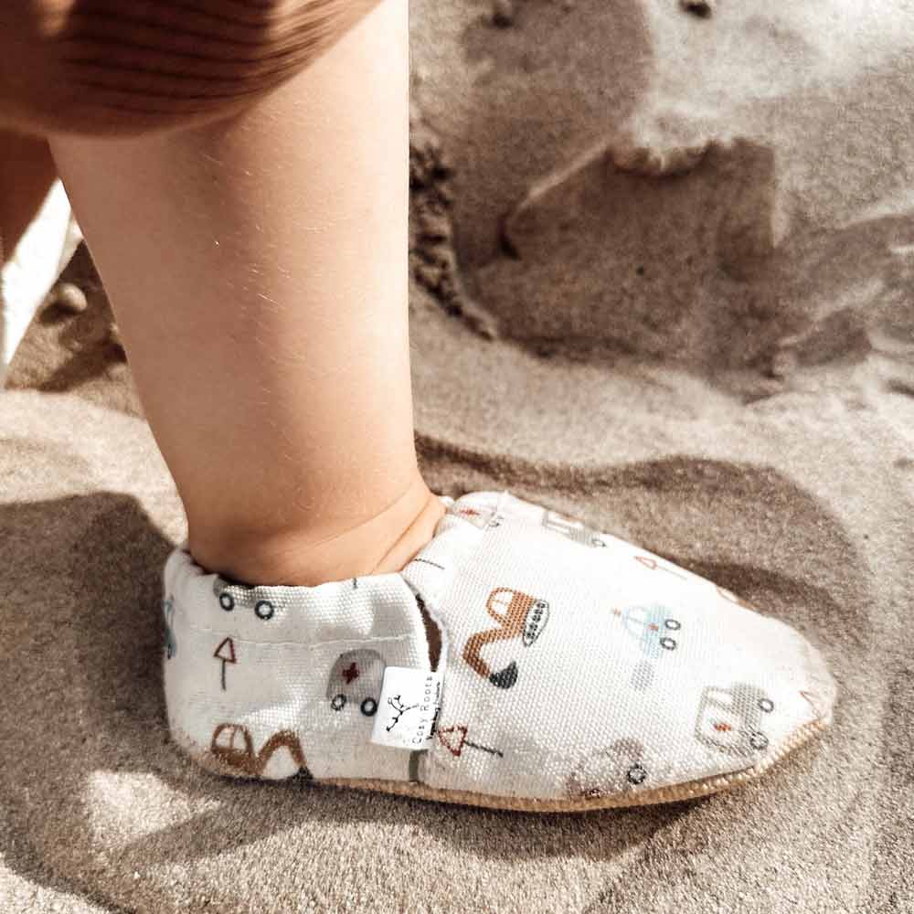 Ein Kinderfuß im Cozy Roots - Lauflernschuh Little Driver mit verspieltem Muster.