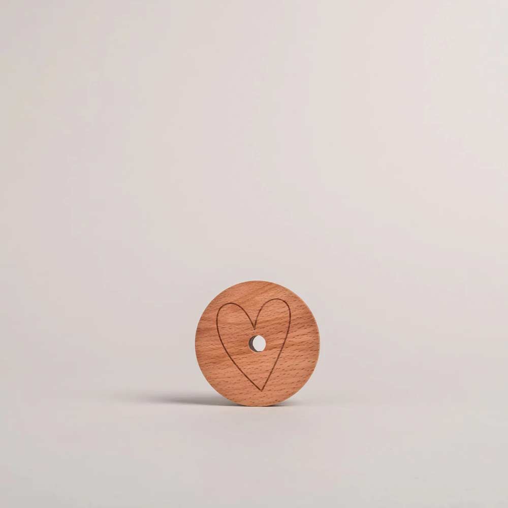 Der Eulenschnitt - Deckel Herz für Hohes Trinkglas, ein runder Holzdeckel mit Herz-Umrissgravur, steht aufrecht vor einem schlichten, hellen Hintergrund.