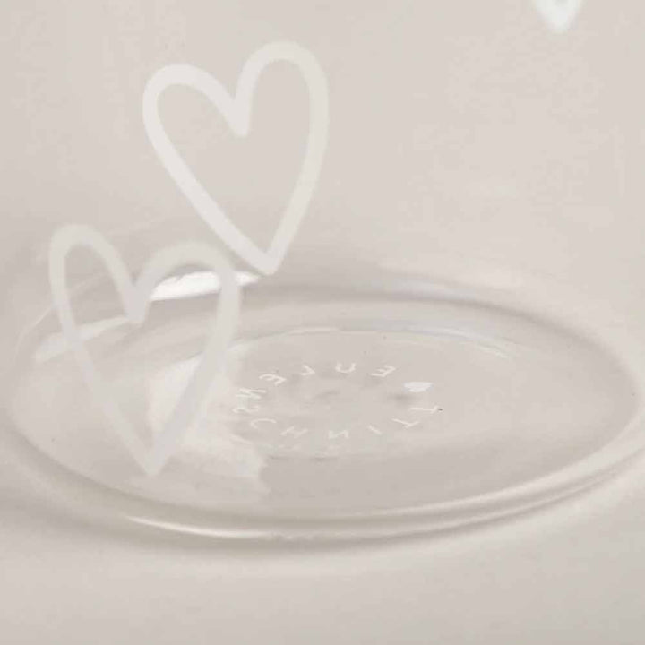 Das Eulenschnitt - Trinkglas Herzen weiß verfügt über eine klare Glasoberfläche, die mit zwei weißen Herzumrissen und dezentem Text am Boden verziert ist.