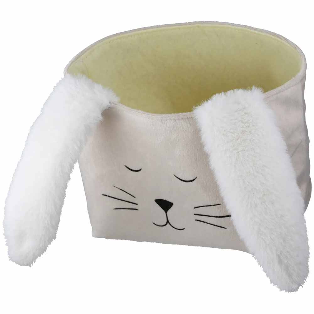 Die Gilde - Ostertasche Schlappi ist ein plüschiger Aufbewahrungskorb im Hasengesichts-Design mit Schlappohren, geschlossenen Augen, Schnurrhaaren und einer kleinen schwarzen Nase.