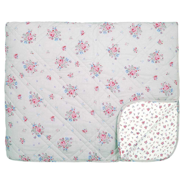 Abgebildet ist ein GreenGate - Elysia Quilt in Hellgrau 140x220 cm mit einem roten und blauen Blumenmuster. Der Quilt ist an einer Ecke nach hinten gefaltet, so dass ein weißes Futter mit einem kleineren Blumendruck zum Vorschein kommt.