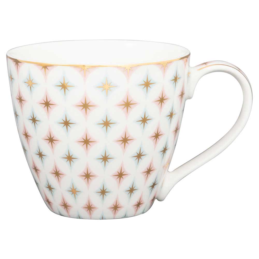 Eine weiße GreenGate - Novella Tasse mit einem goldenen und rosa Sternenmuster und einem gebogenen Henkel.