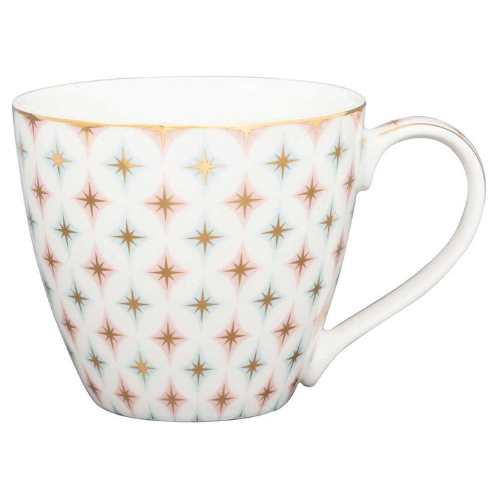 Eine weiße GreenGate - Novella Tasse mit einem goldenen und rosa Sternenmuster und einem gebogenen Henkel.