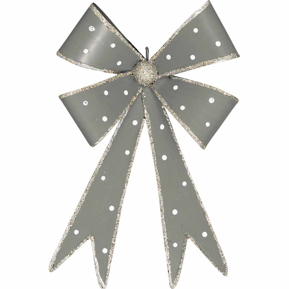 Eine GreenGate - Schleife Metall mit glitzernden Kanten und einem Knoten in der Mitte, geschmückt mit langen, herabhängenden Bandenden.