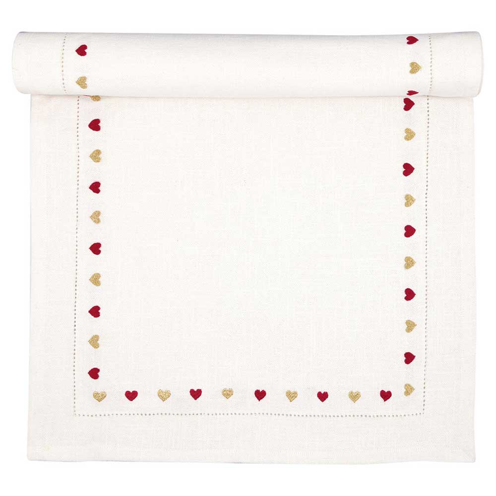 Ein GreenGate - Tischläufer Grace weiß mit Stickerei, verziert mit rot-goldener herzförmiger Stickerei entlang der Kanten, an einem Ende teilweise gerollt.
