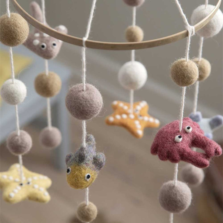 Ein Gry &amp; Sif – Baby-Mobile „Unterwasserwelt“ mit Meeresbewohnern aus Filz und weichen Bällen in verschiedenen Pastellfarben, darunter ein Oktopus, ein Fisch und ein Seestern.