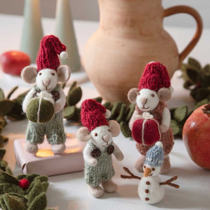Drei Gry & Sif Babymaus Filz mit grünem Schlauch Figuren mit Winteraccessoires neben einer kleinen Schneemannfigur und festlichen Dekorationen.