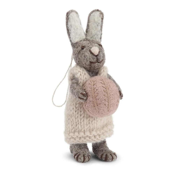Ein hellgrauer Gry & Sif - Hase Filz mit Ei in einem weißen Kleid mit einem rosa Ei.