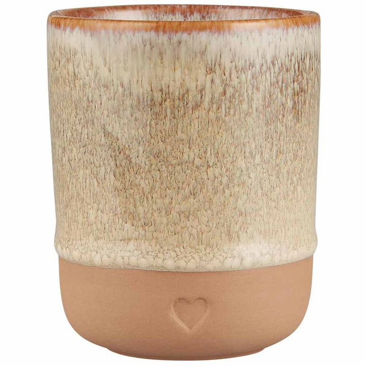 Der Ib Laursen Becher Herz Ton Natur ist eine Keramiktasse mit einer strukturierten beigen oberen Hälfte, einer glatten braunen unteren Hälfte und einem kleinen geprägten Herz in der Nähe der Basis.