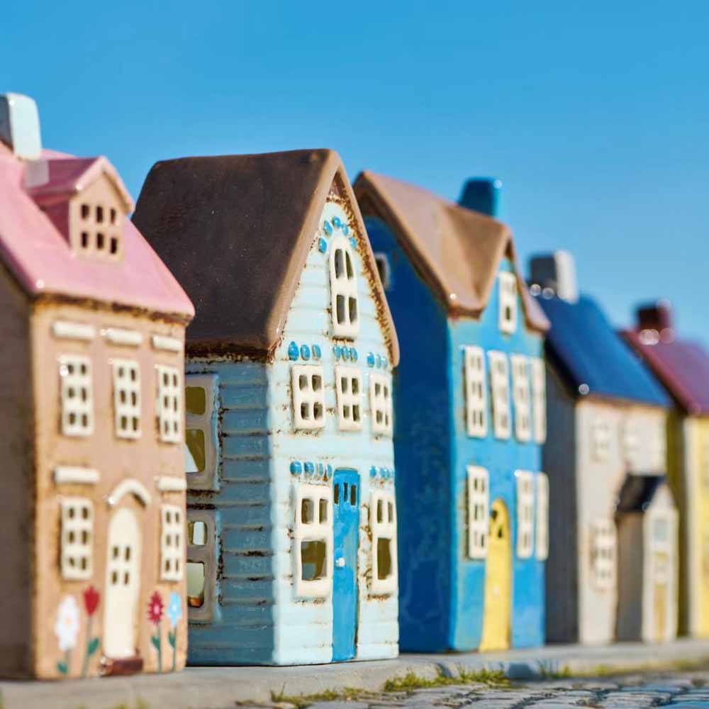 Das Ib Laursen Haus für Teelicht Nyhavn mit Blumen und rosa Dach präsentiert sich als farbenfrohes Keramik-Miniaturhaus vor klarem, blauem Himmel.