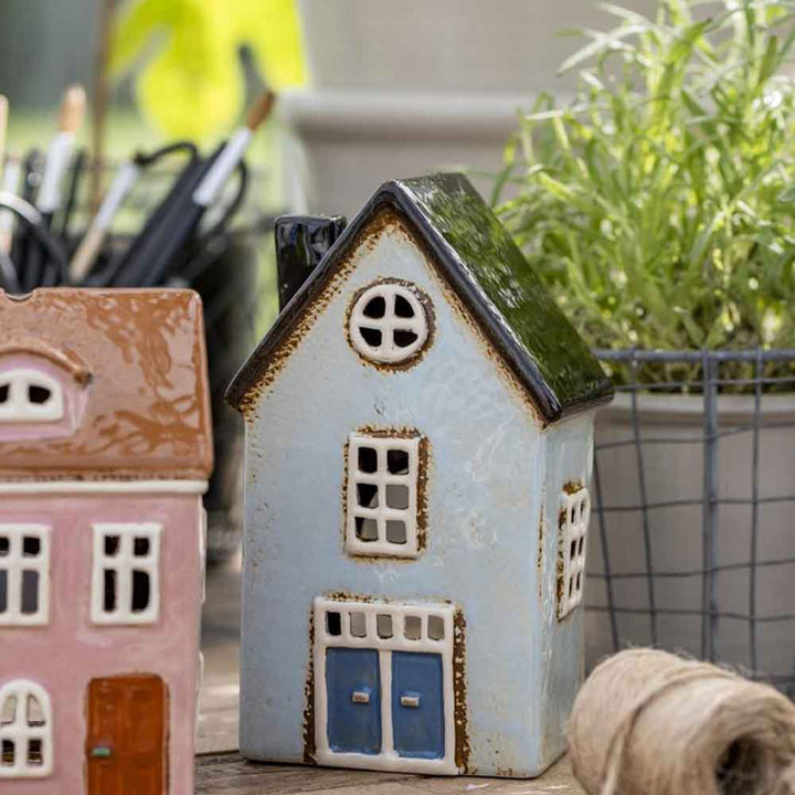 Zwei kleine Ib Laursen - Haus für Teelicht Nyhavn gerundete Dachfenster auf einem Tisch, umgeben von Stiften, einer Topfpflanze und einer Rolle Bindfaden.