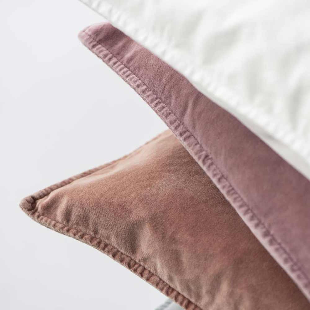 Nahaufnahme von drei gestapelten Kissenbezügen aus Ib Laursen-Velours-Buttercreme (72 x 52 cm) mit sichtbaren Nähten in Weiß-, Mauve- und Altrosa-Tönen.