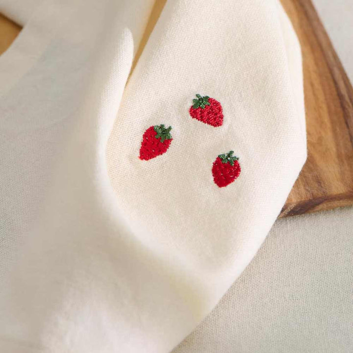 Buttercremefarbene Stoffserviette mit drei gestickten Erdbeeren aus der Summer Vibes-Kollektion von Ib Laursen.