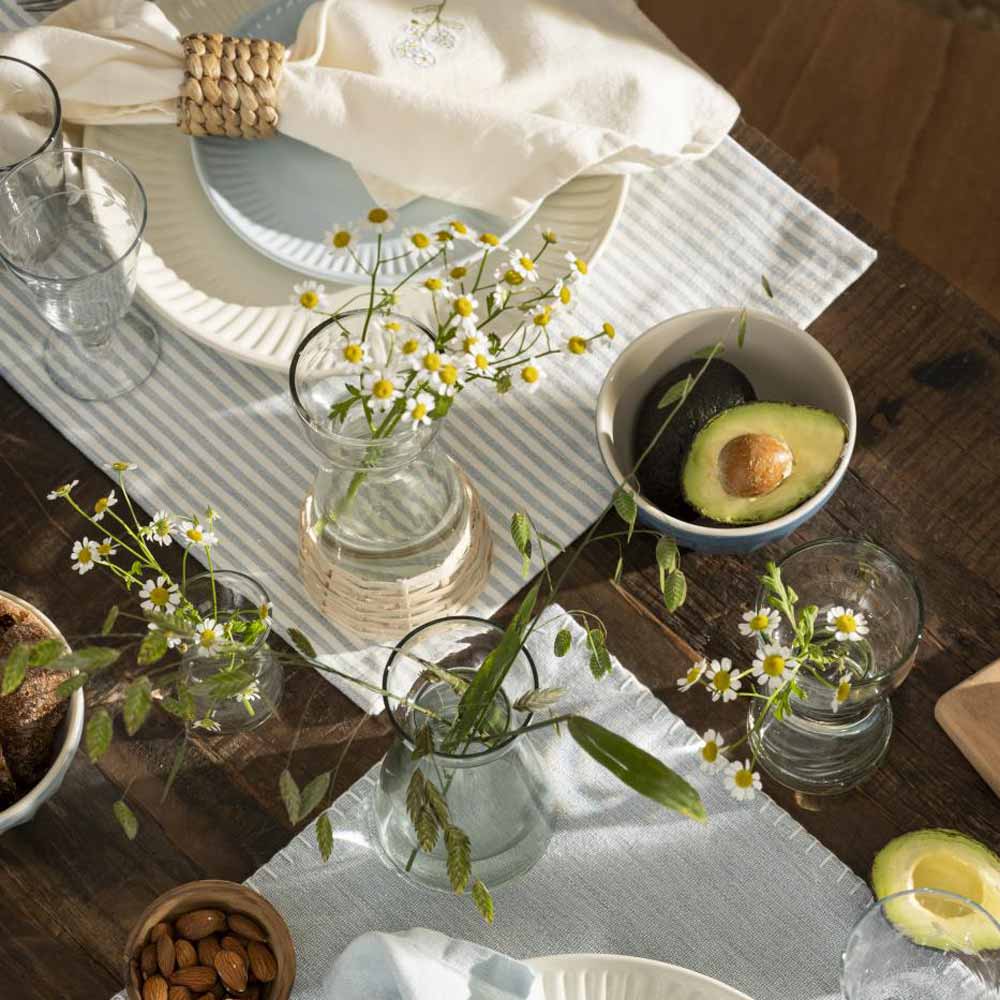 A Ib Laursen - Tischset staubig blau mit weissen Streifen mit Tellern und Gläsern und Blumen.