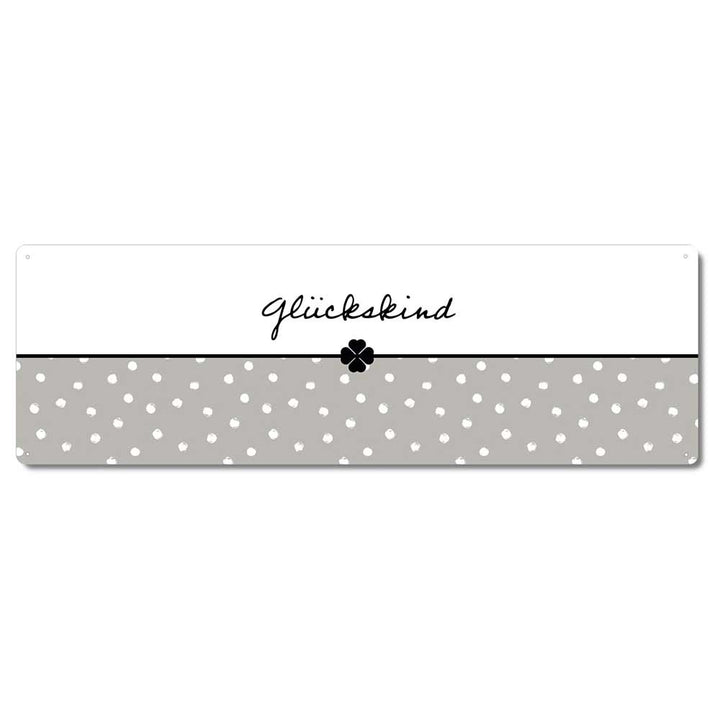 Ein rechteckiges Schild mit dem deutschen Wort „Glückskind“ in handgeschriebener Schrift über einem schwarz-weißen vierblättrigen Kleeblatt. Die untere Hälfte des Schildes hat ein graues Tupfenmuster. Es handelt sich um das Interluxe Metallschild – Glückskind.