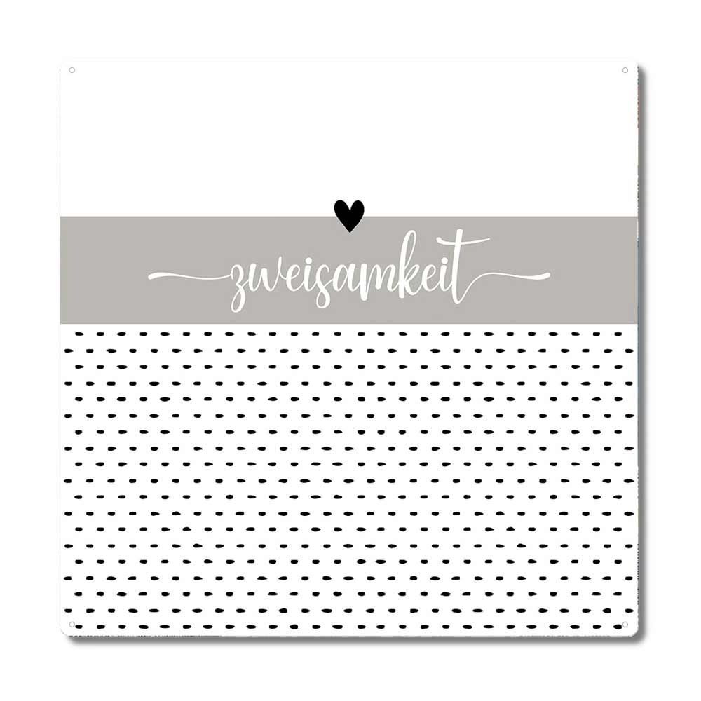 Ein quadratisches Design mit weißer Oberseite, grauem Mittelteil mit dem Wort „Interluxe Metallschild – Zweisamkeit“ in Kursivschrift und einem Herzsymbol sowie weißer Unterseite mit verstreutem schwarzen Punktmuster.