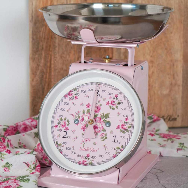 Eine rosa, floral gemusterte Isabelle Rose - Küchenwaage Retro auf einer Holzoberfläche.