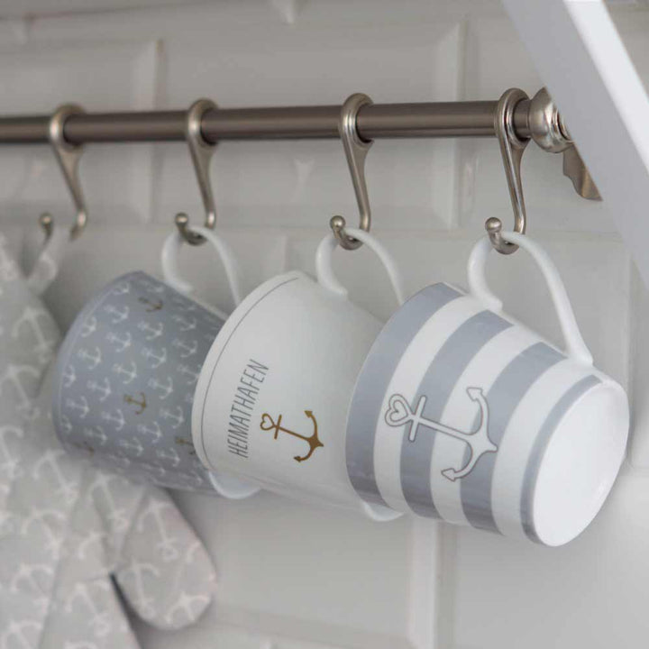 Drei Krasilnikoff - Happy Cup Anker graue Streifen hängen an Haken an einer Metallstange.