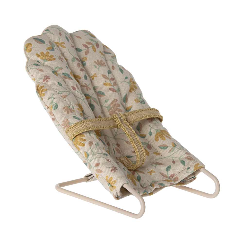 Ein Maileg - Babysitter Mikro mit Blumendruck in Beige und Gelb, befestigt auf einem einfachen Metallrahmen.